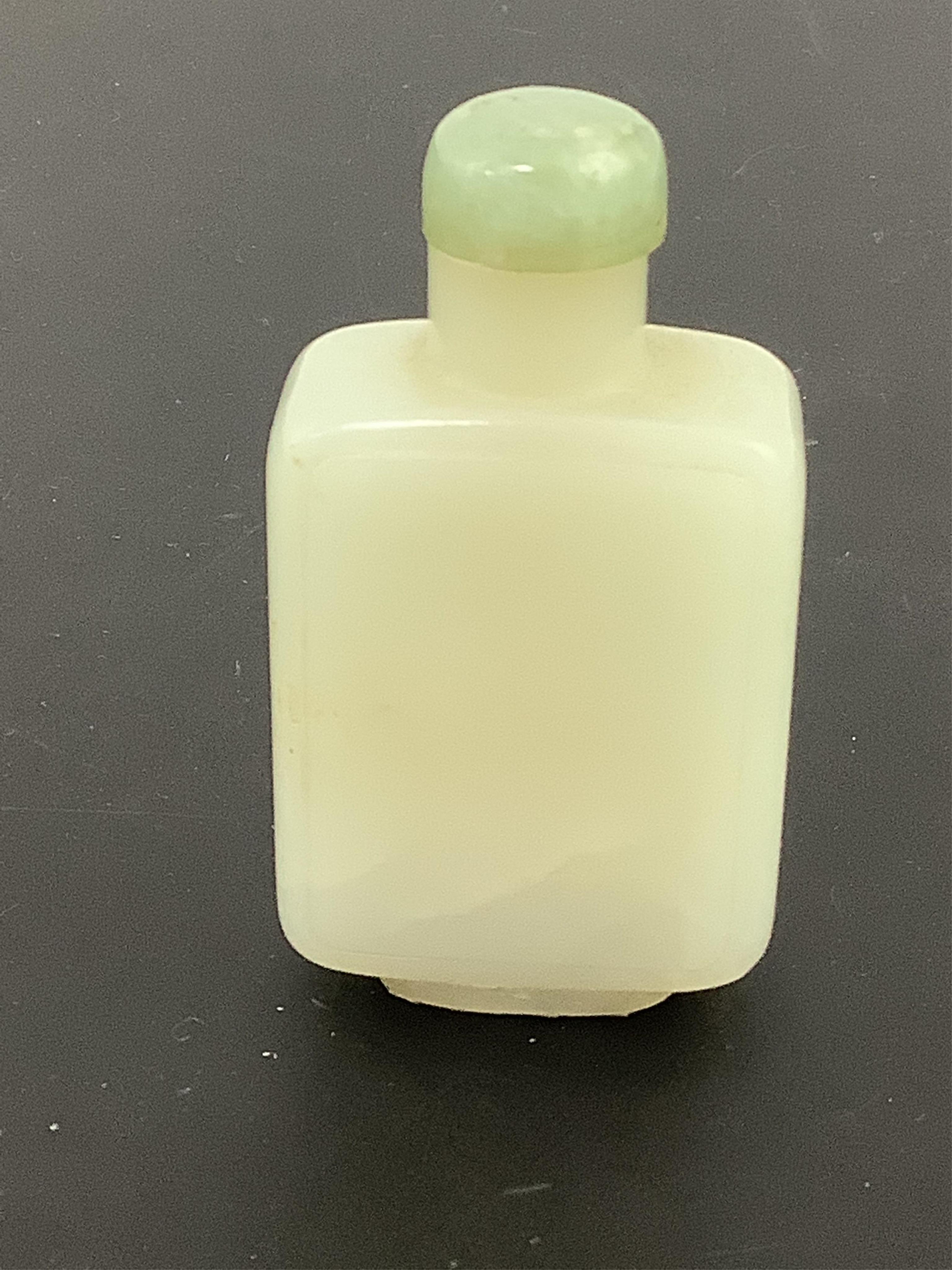 A Chinese pale celadon jade snuff bottle, 19th century, of rectangular form with a raised panel to each side, the stone with a few white inclusions, 5.7cm high. Condition - good